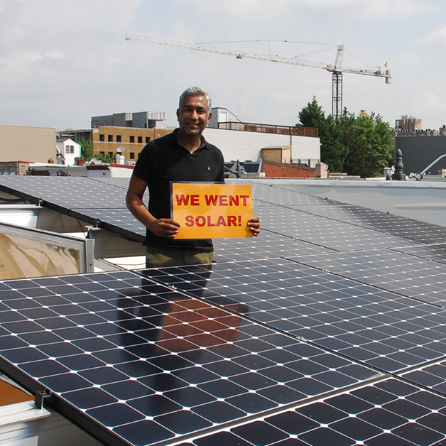 solar owner in DC on rooftop surrounded by solar panels in their solar energy system