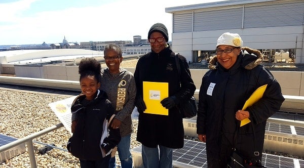 Shiela Credel (middle) and other recipients of electricity bill credits from the first community solar project in D.C. enjoyed seeing some of the panels that make up the solar system.