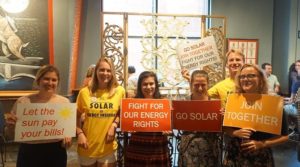 Solar supporters hold signs reading Go Solar, Join Together, and Fight for our Energy rights!