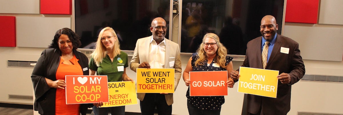 Group of DC residents holding signs about going solar