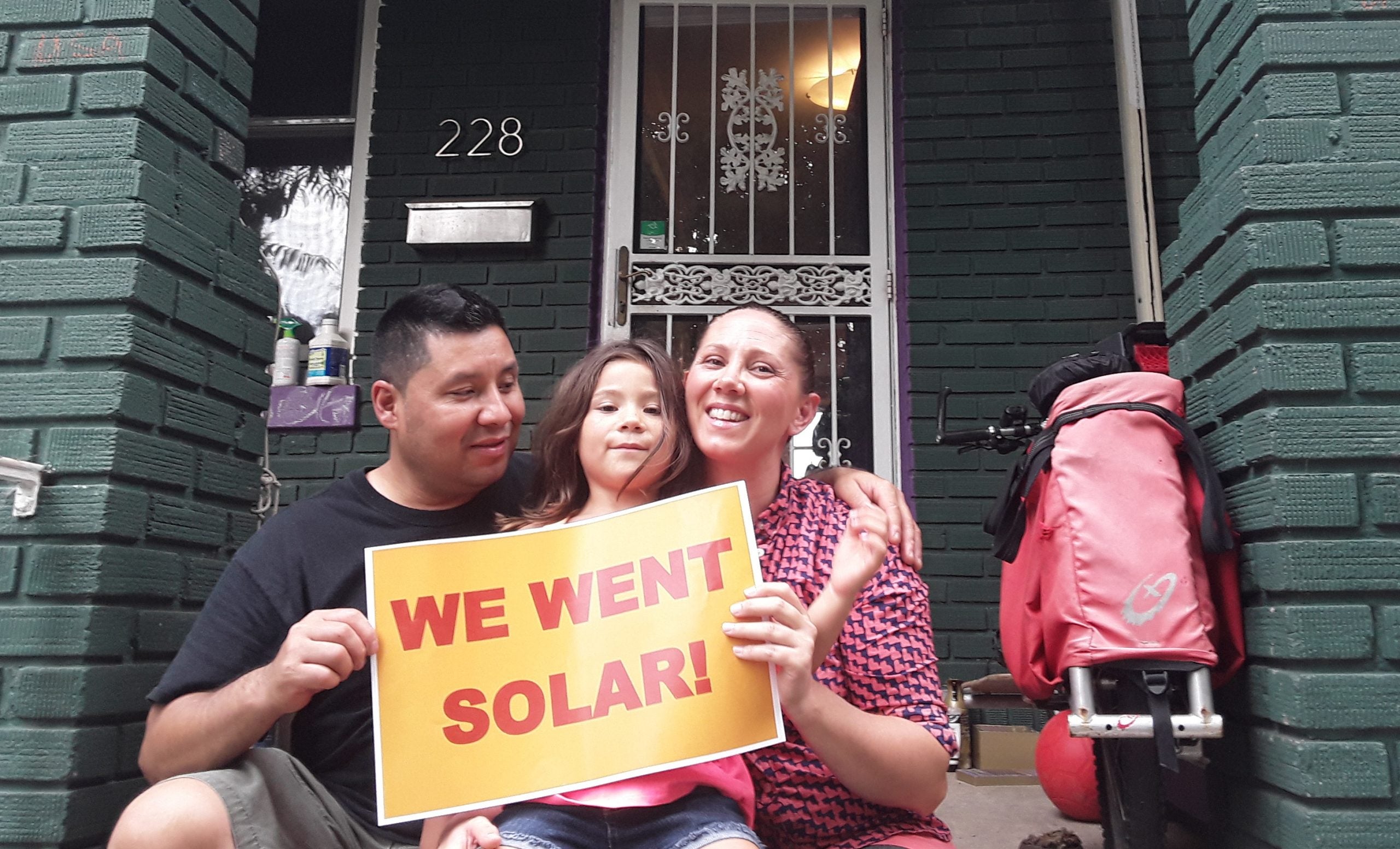 Pergola family holding "we went solar" sign on front porch