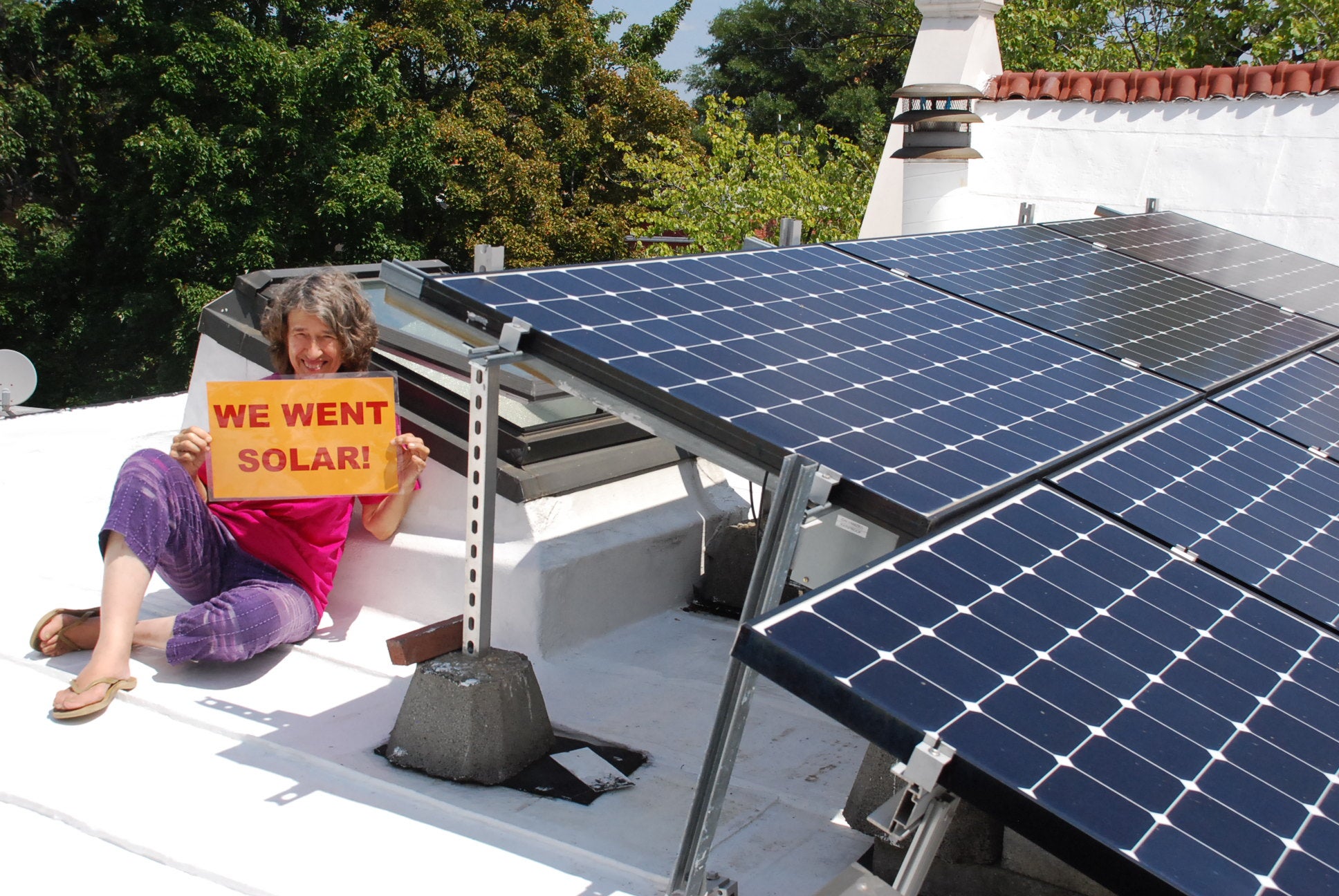 DC solar homeowner on roof with new solar system and sign reading: we went solar